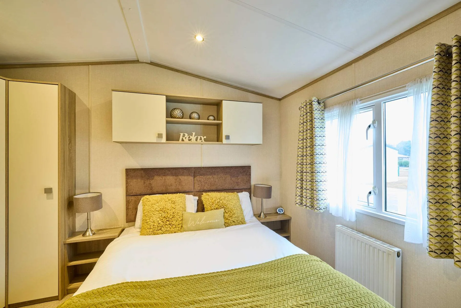 Un dormitorio con una cama bien hecha y una ventana grande a su lado.