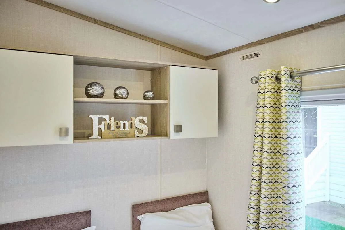 Un dormitorio con armarios superiores, objetos decorativos y una ventana con cortina.