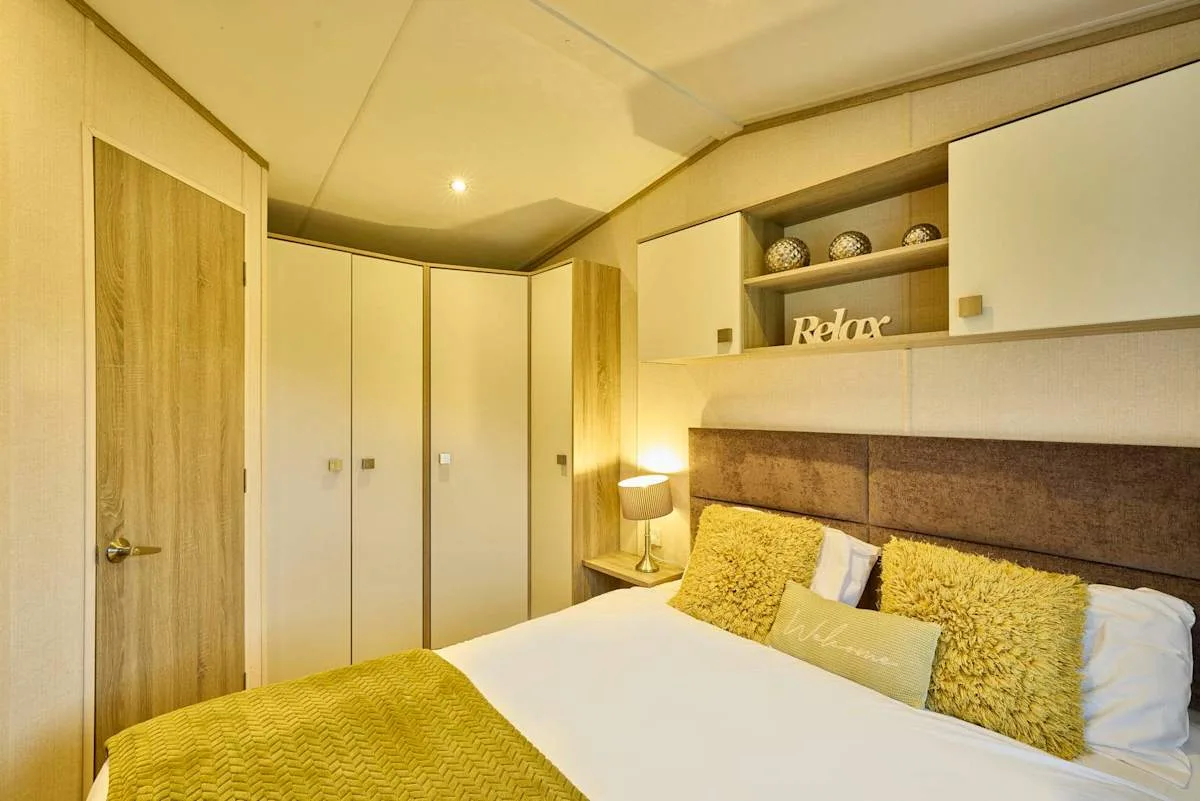 Un dormitorio con una cama doble, una lámpara de noche y armarios empotrados.