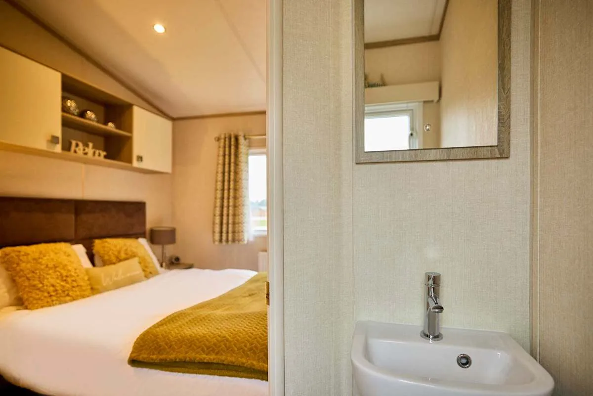 Un dormitorio con una cama junto a una pequeña zona con lavabo.