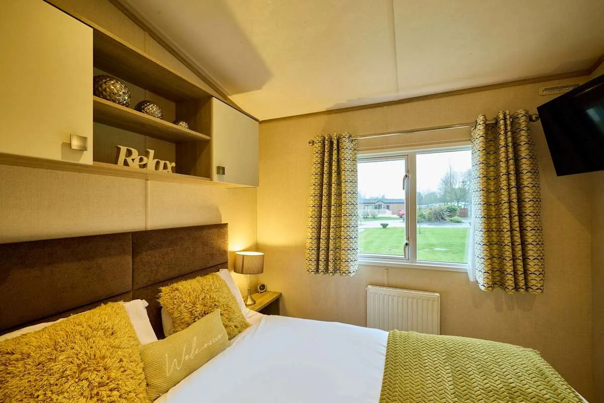 Dormitorio con una cama, cortinas estampadas y una ventana con vistas a zonas verdes.