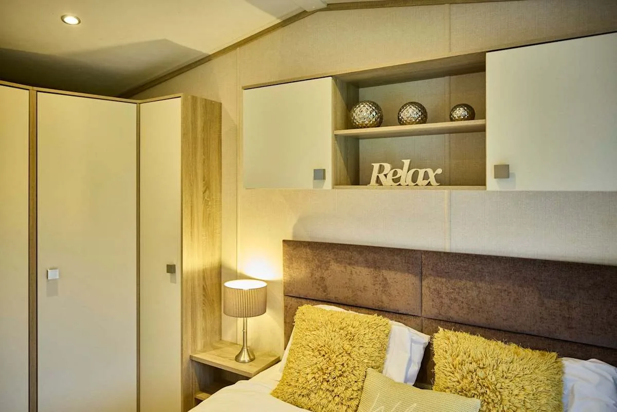 Un dormitorio con cama, lámpara de noche y estanterías empotradas.