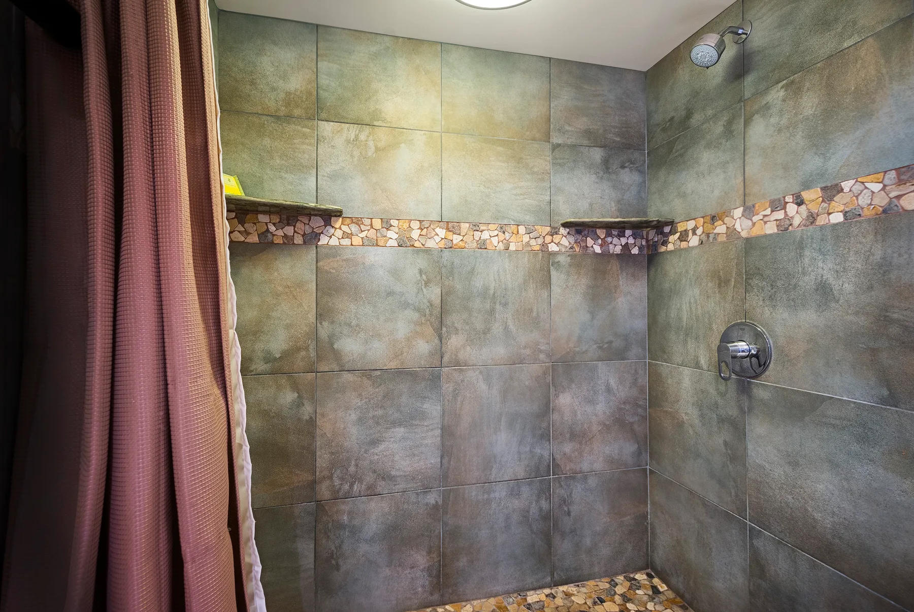 Una zona de ducha con azulejos, cortina y accesorios en la pared.