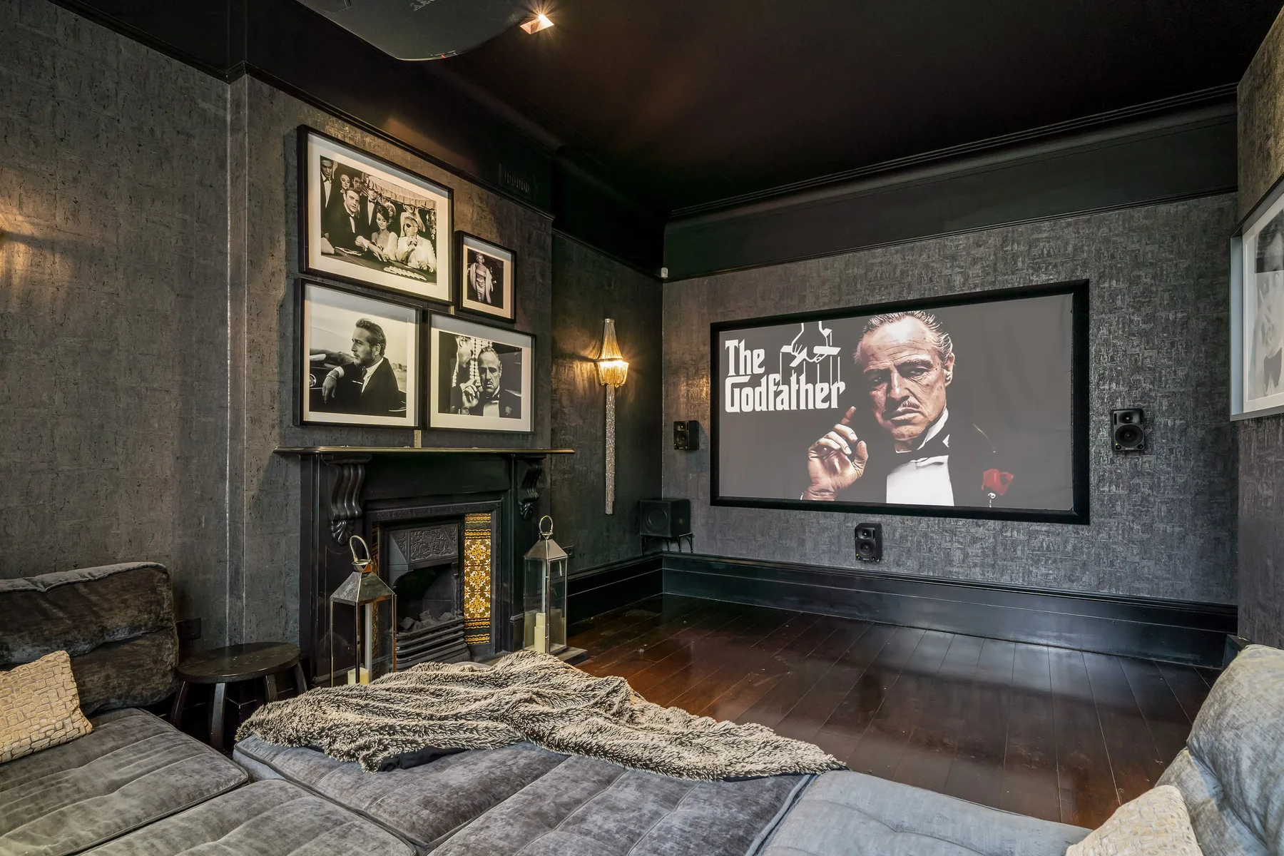 A dark living room features a large screen displaying a film poster.