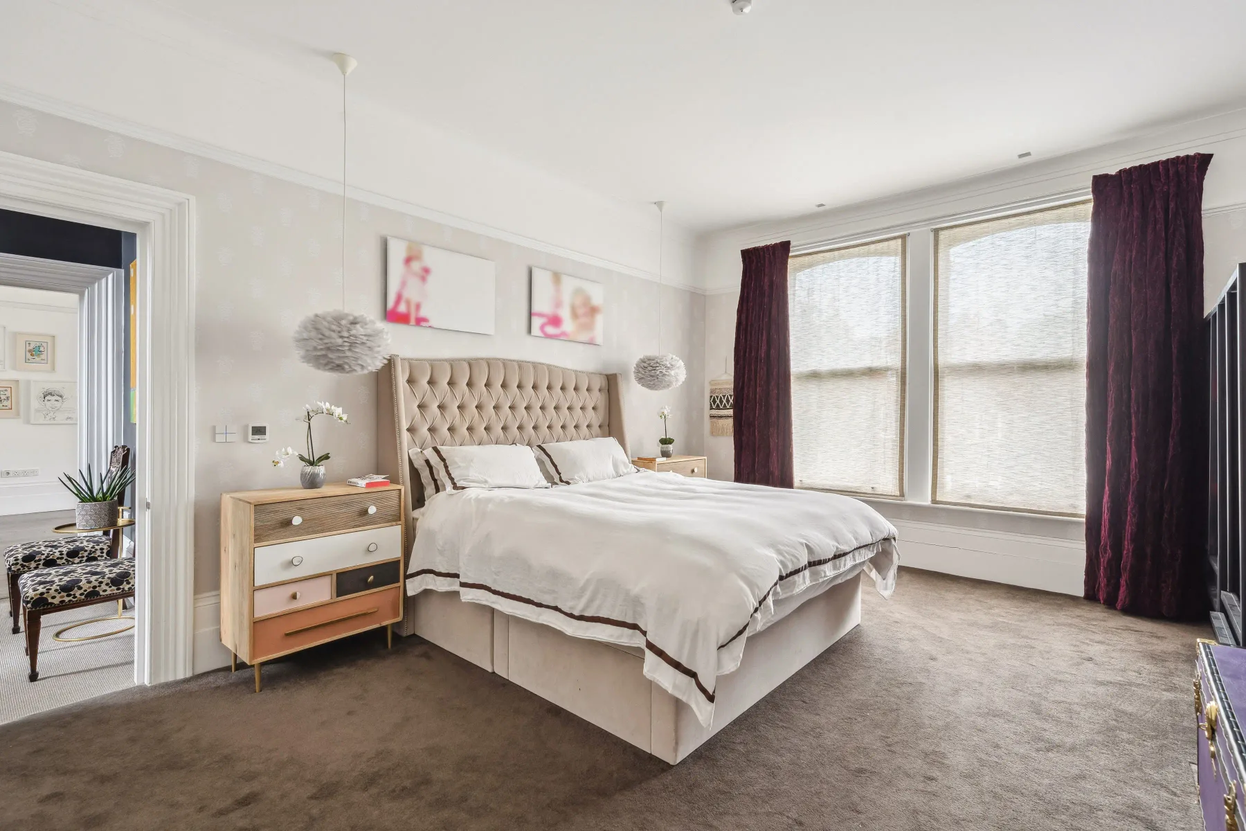 Un dormitorio con una cama tapizada y grandes ventanas.