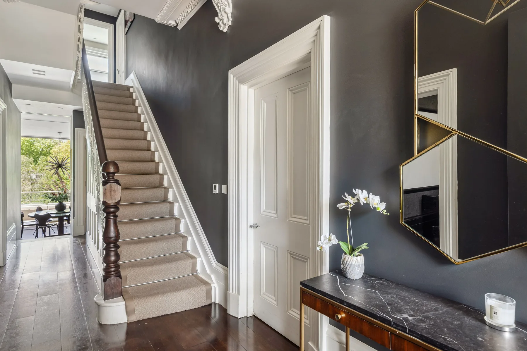 A dark-walled entry hall features a staircase and a white paneled door.