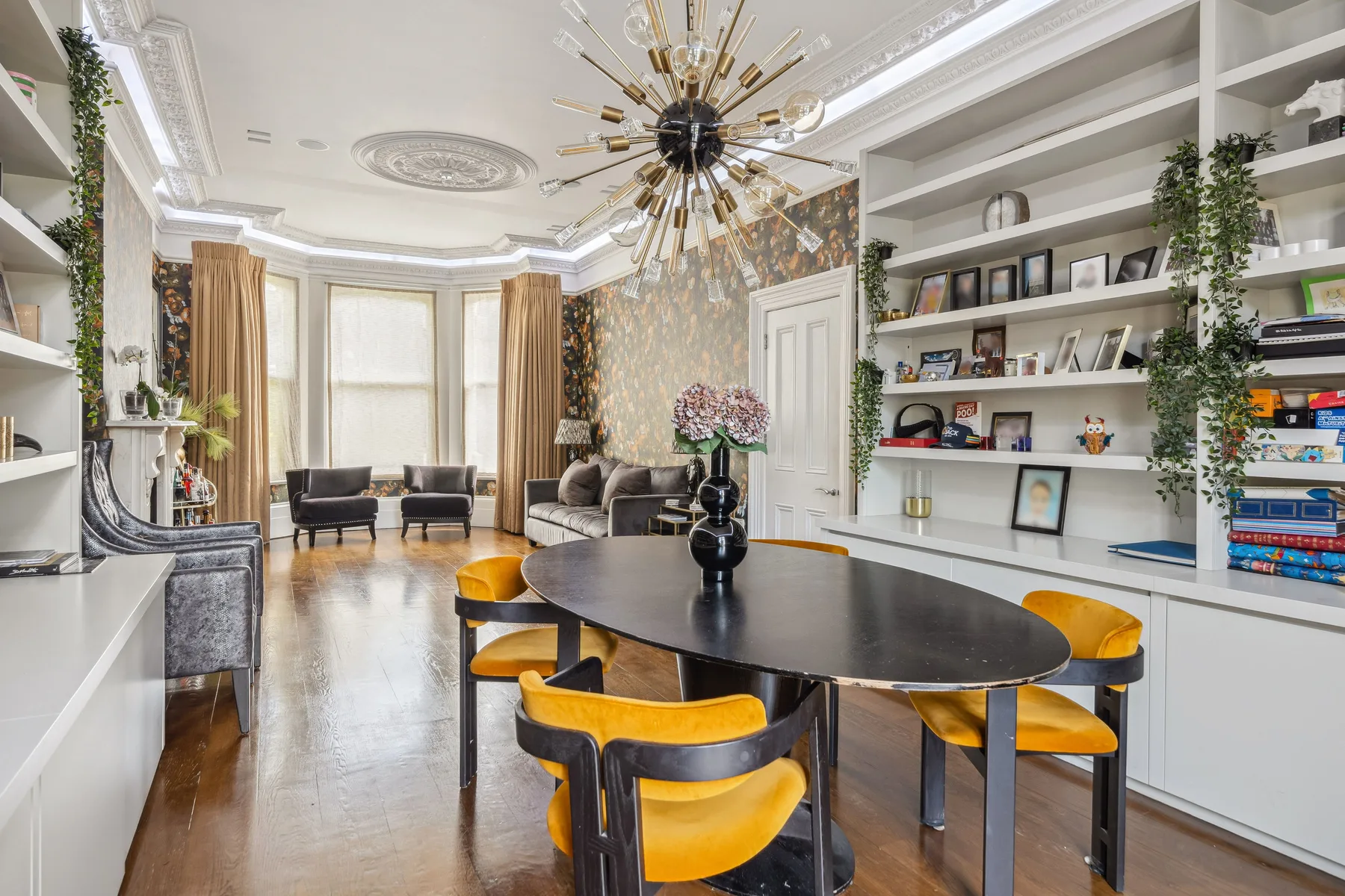 Un luminoso comedor y sala de estar con una mesa larga y estanterías empotradas.