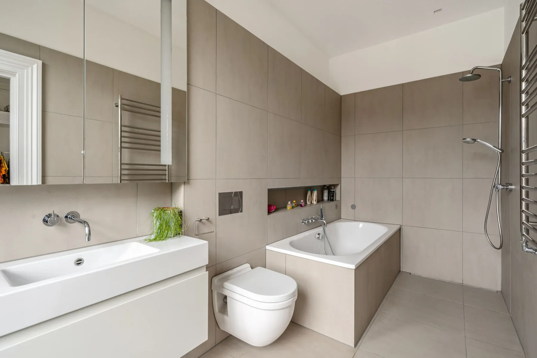 Un baño alicatado con bañera, lavabo y ducha de pared.