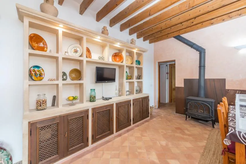 A living room with built-in shelving, a television, and a freestanding stove.
