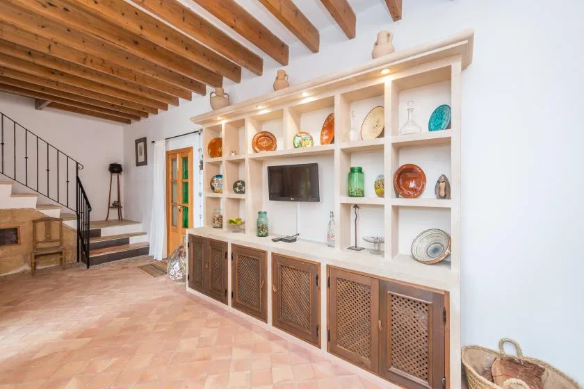 A bright living area features a built-in display cabinet and exposed wooden ceiling beams.