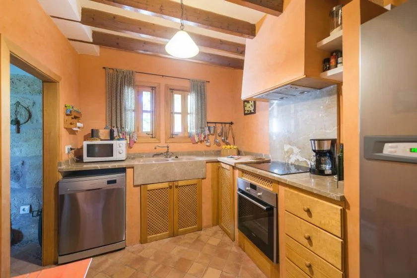 A warm-toned kitchen with wooden cabinets, a countertop, and a window.