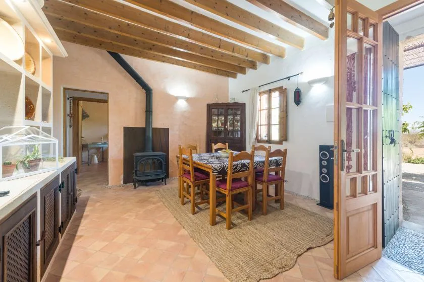 A dining area with a wooden table and chairs beneath exposed ceiling beams.