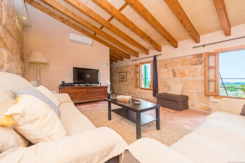 A living room with seating, a coffee table, and exposed wooden ceiling beams.