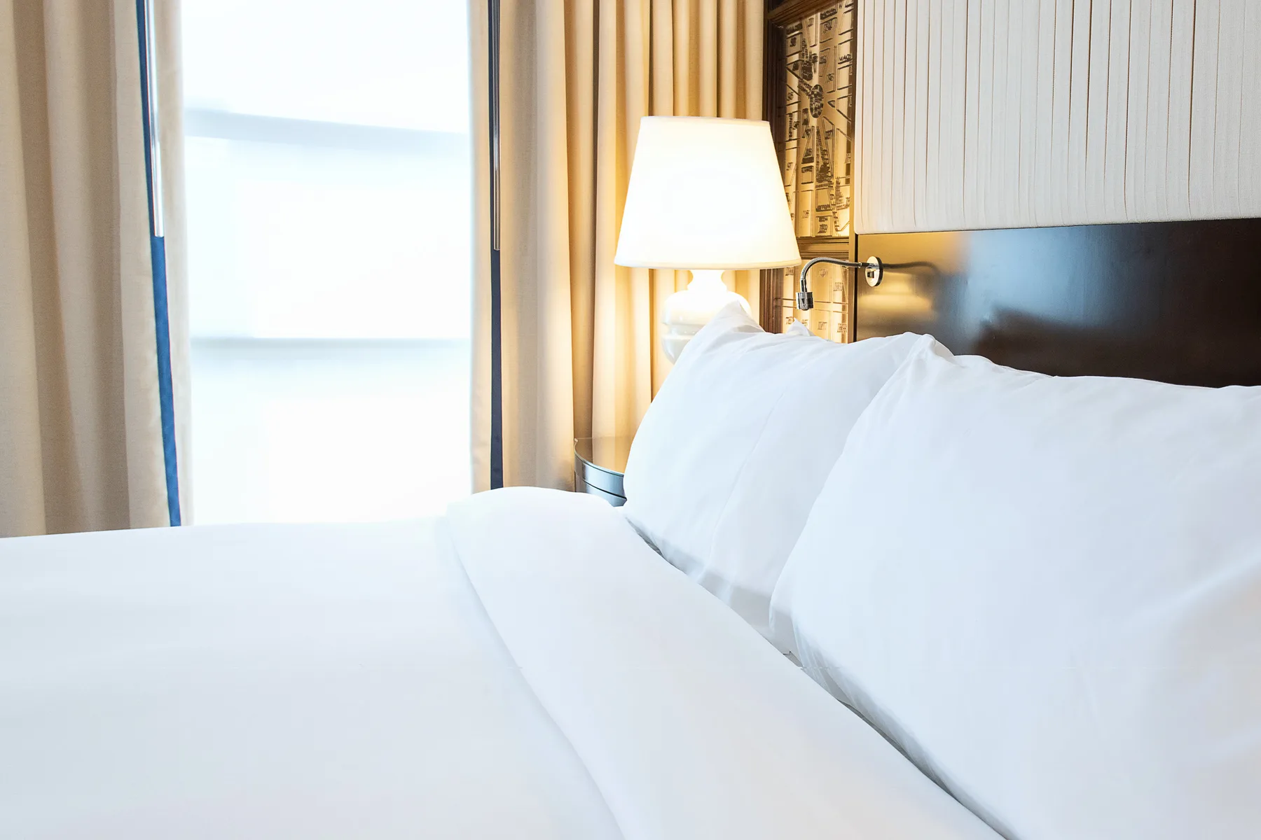 Ropa de cama blanca junto a una lámpara de noche