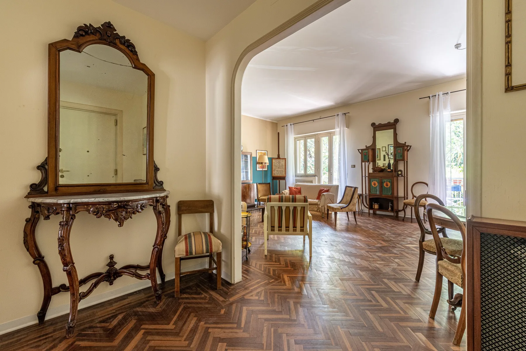 Una sala amueblada con ventanas altas y un suelo pulido con dibujos.