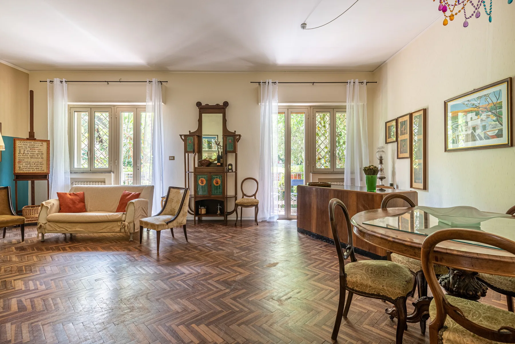 Sala de estar y comedor amueblados, con ventanas altas y suelo de madera estampado.