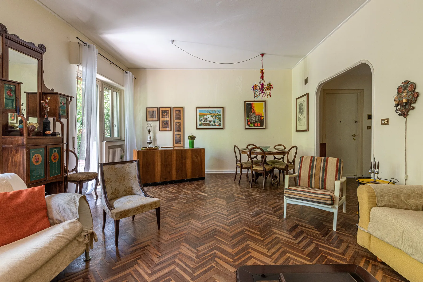 Una sala de estar con mesa de comedor, asientos coloridos y cuadros enmarcados.
