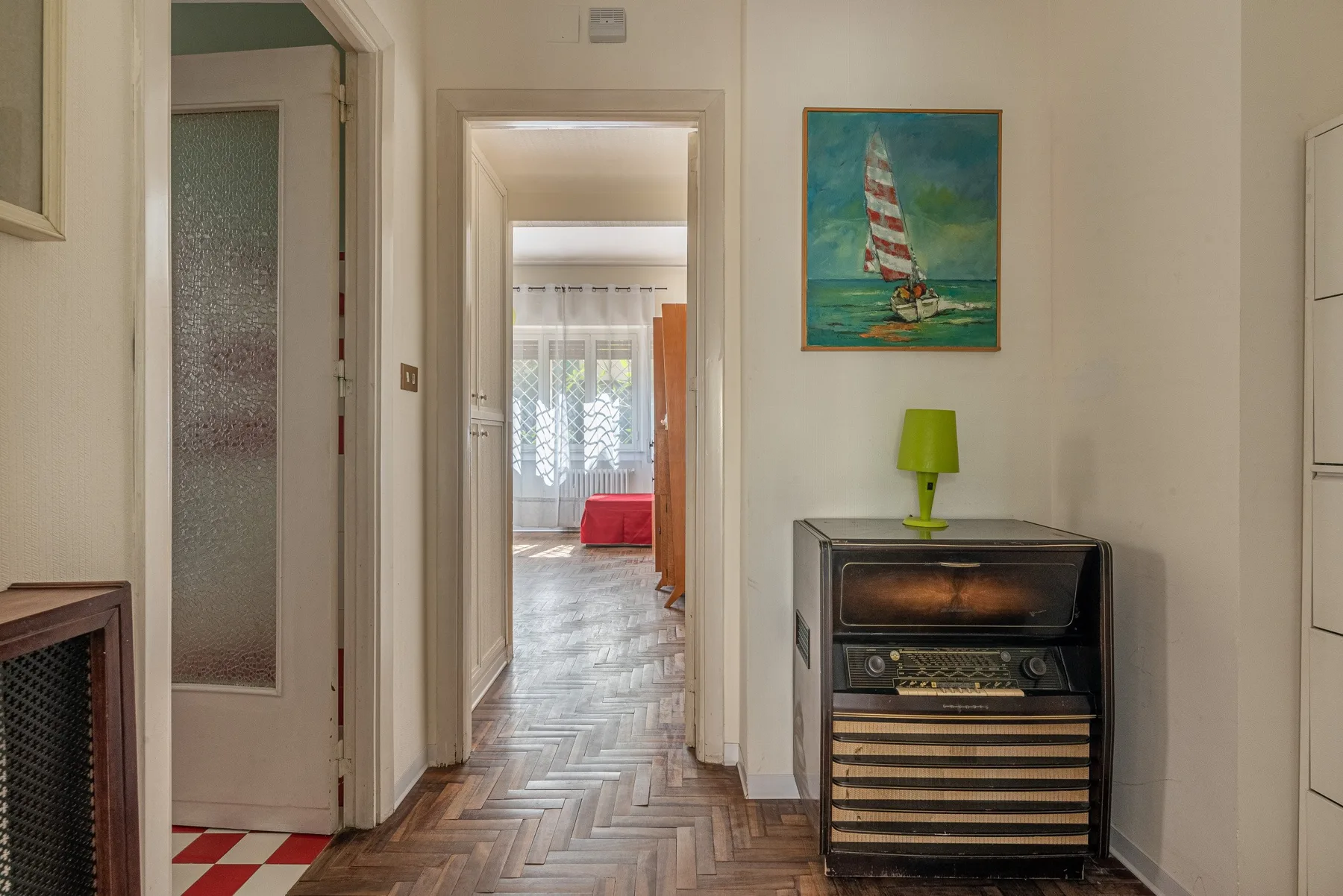 Un pasillo con un cuadro enmarcado de un velero sobre un mueble pequeño.