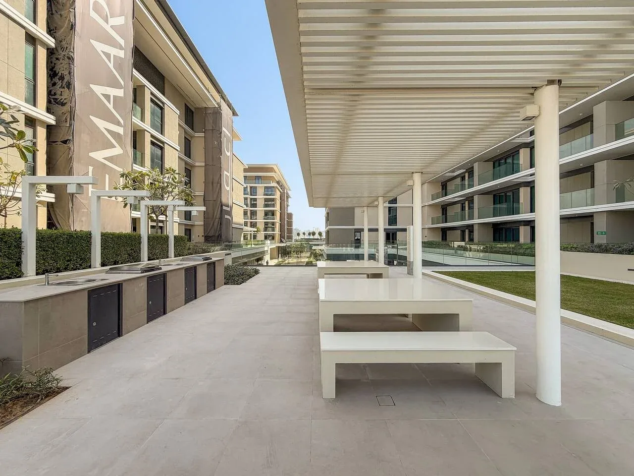 A paved outdoor courtyard with built-in seating beneath a covered walkway.