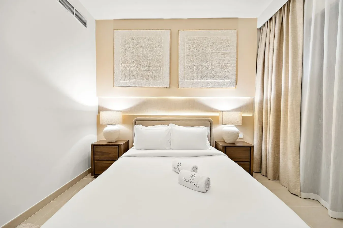 A bright bedroom with a neatly made bed and curtains along the window.