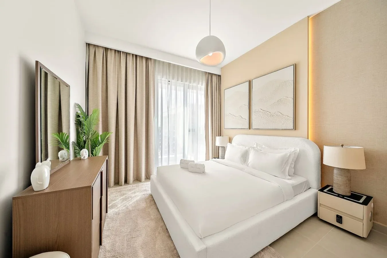A bright bedroom with a neatly made bed, bedside tables, and curtains.