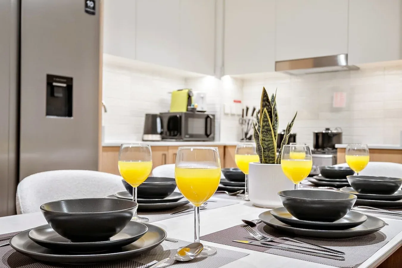 A dining table set with dishes and drinks in a bright kitchen.