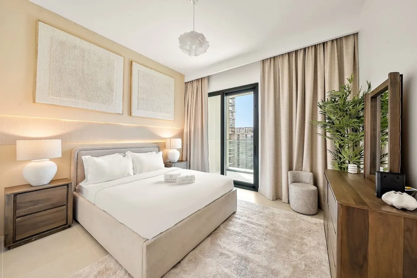 A bedroom with a neatly made bed and curtains beside a glass door.