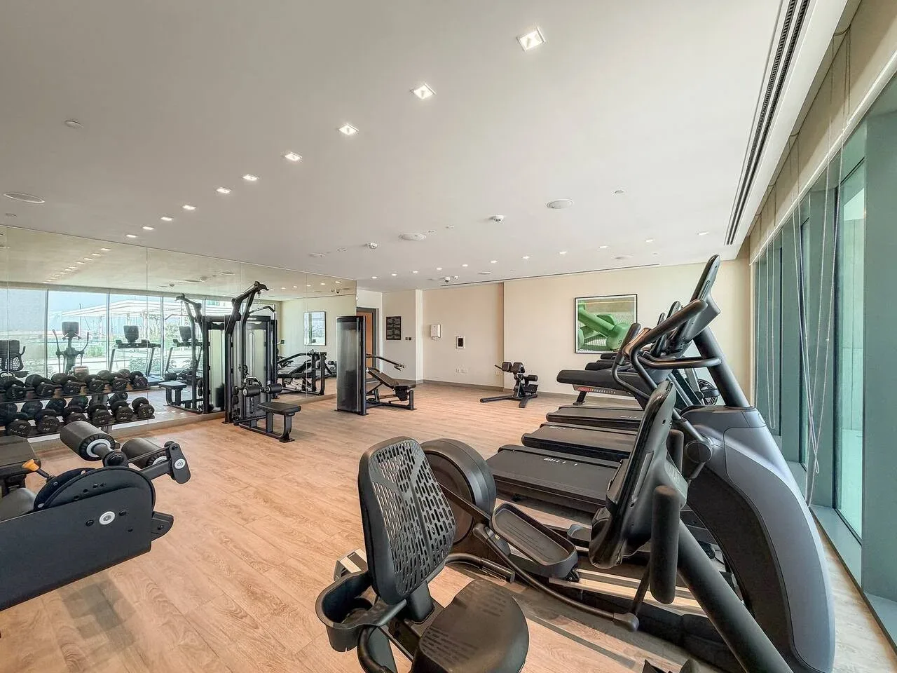 A bright fitness room with exercise machines, treadmills, and weights.