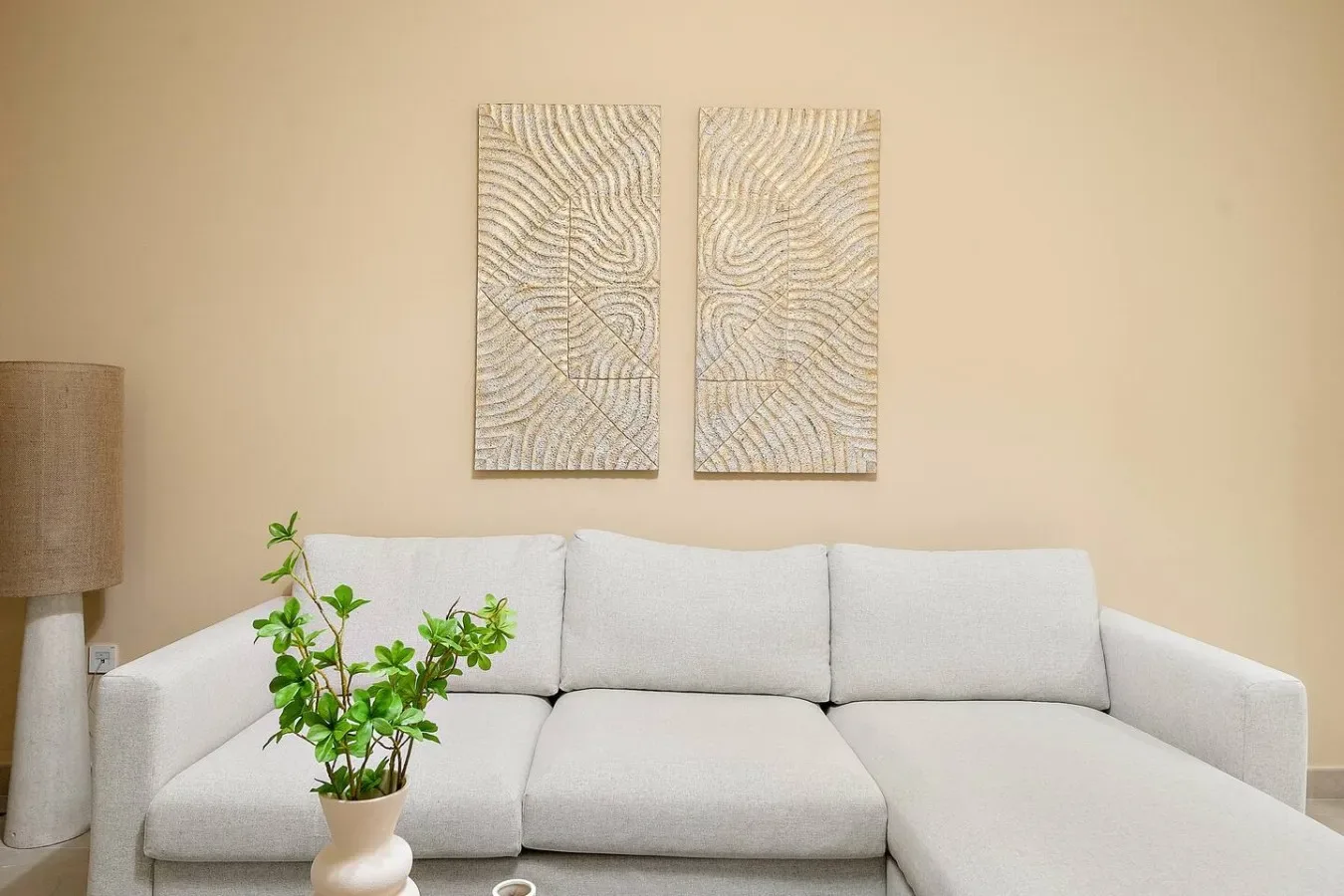 A bright living room with a light sectional sofa and two abstract wall prints.
