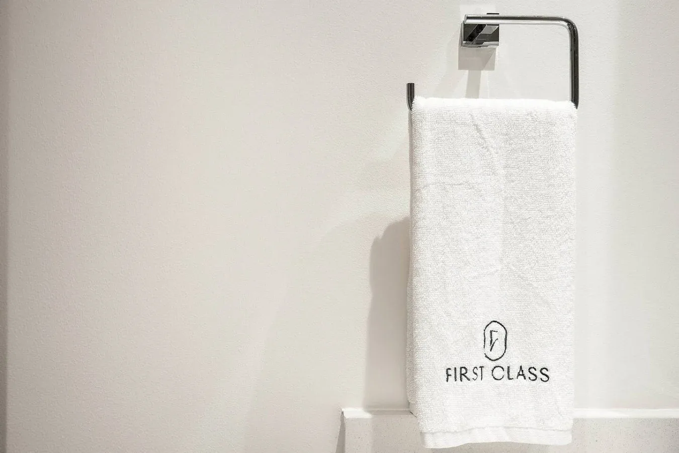 A white towel hangs from a metal rack against a plain bathroom wall.