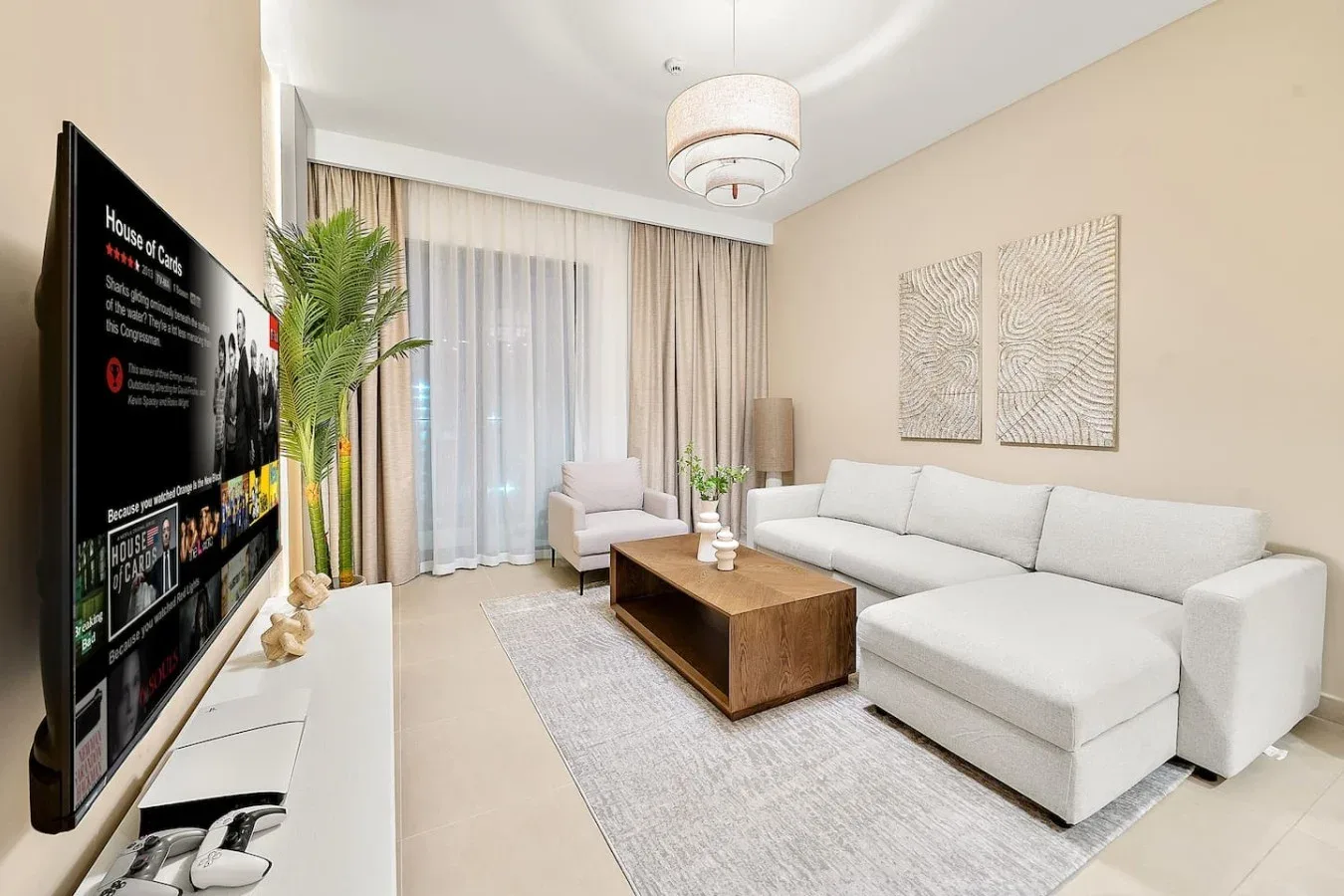 A bright living room with a sectional sofa, coffee table, and large curtained windows.