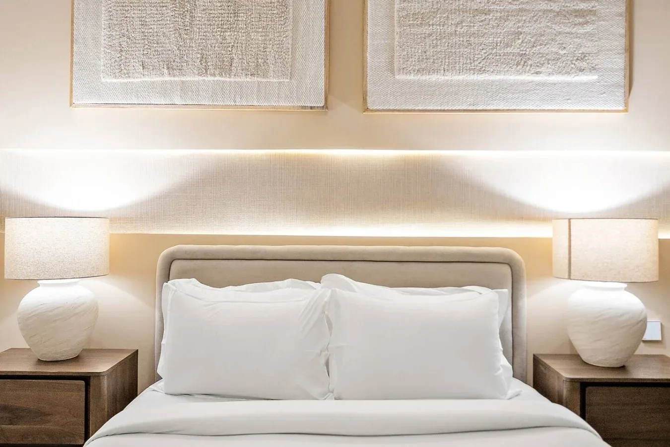 A bedroom with a neatly made bed and matching bedside lamps.