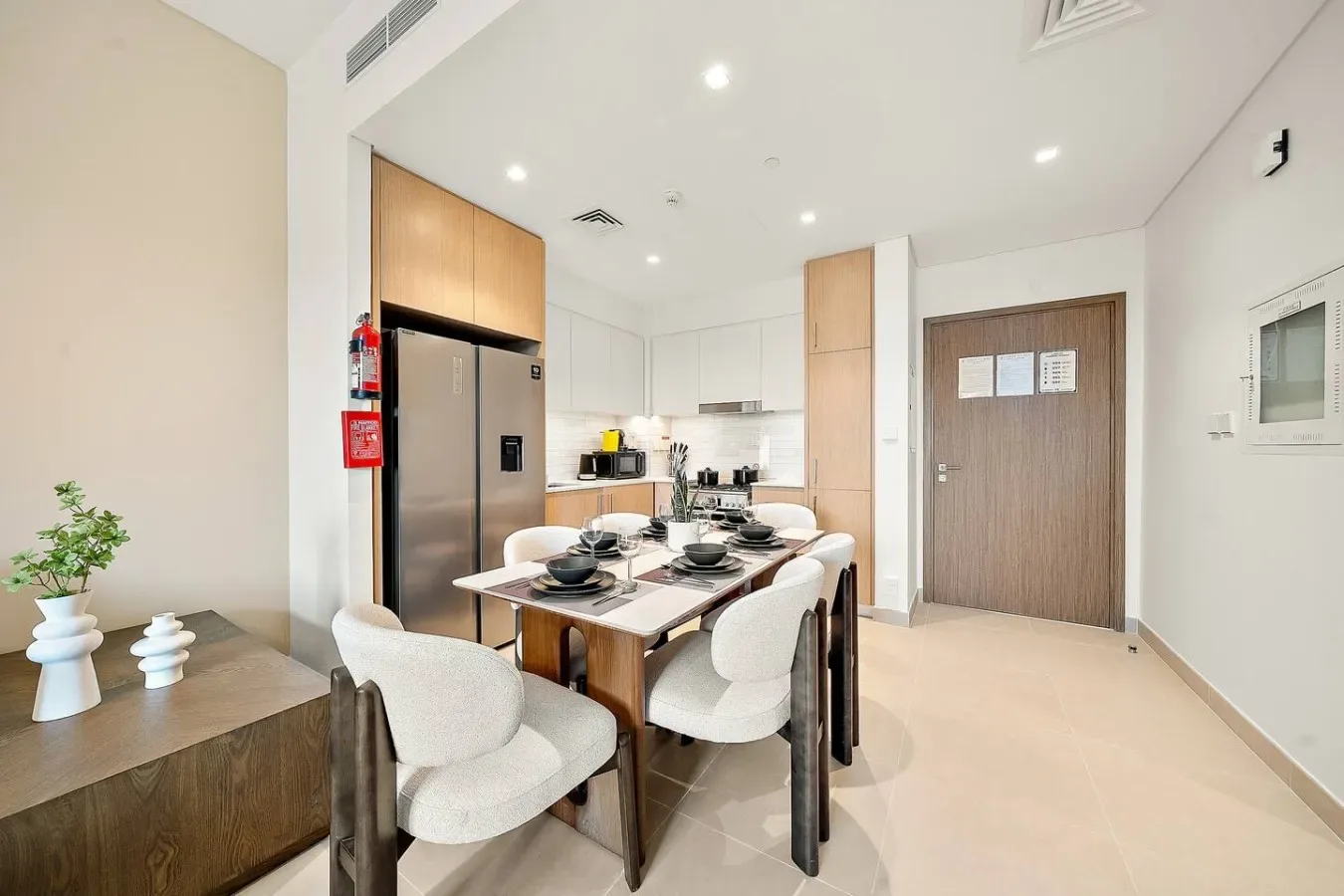 Un comedor con la mesa puesta está junto a una cocina compacta.