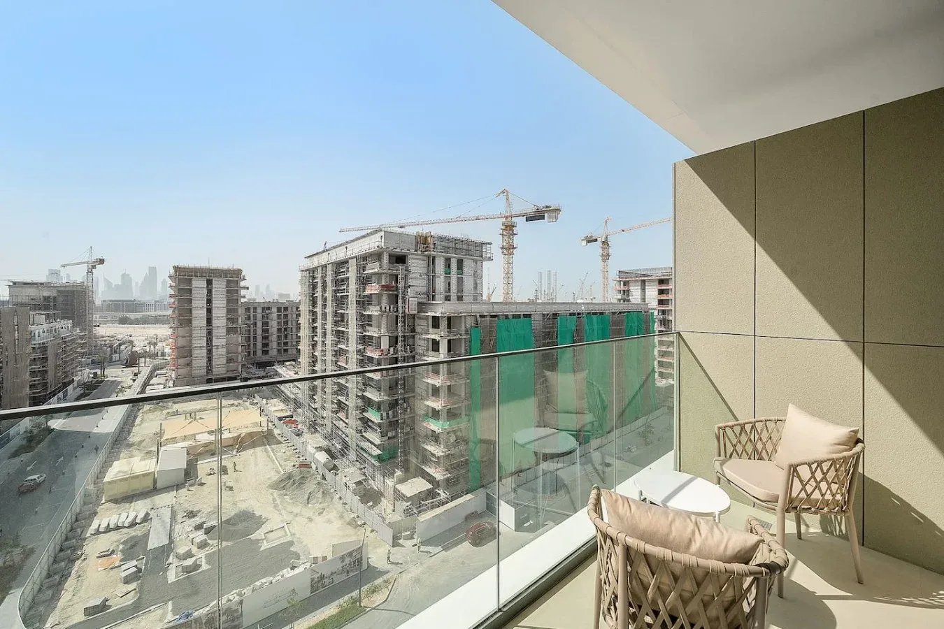 A balcony with seating overlooks a large construction site.