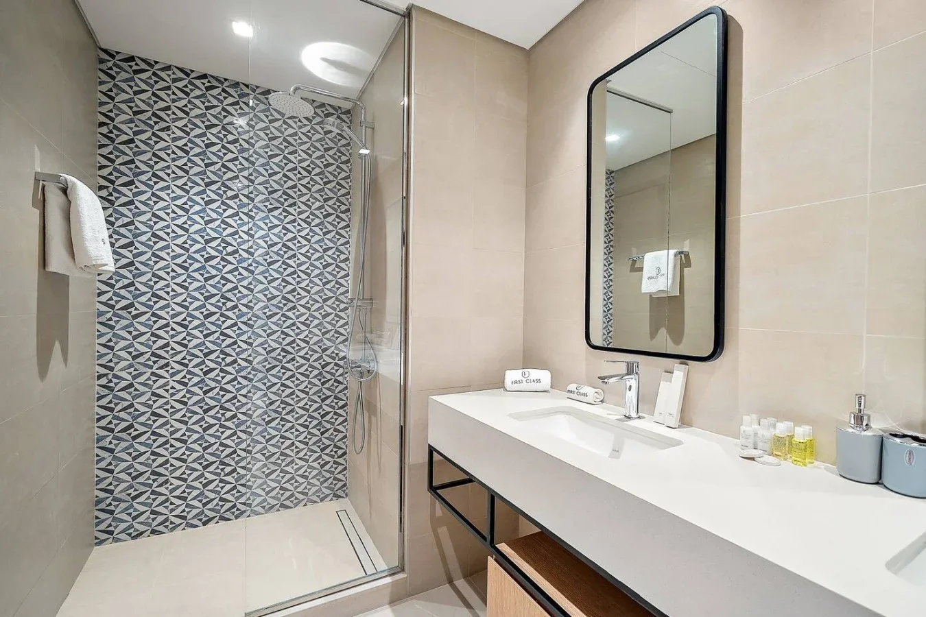 A modern bathroom with a glass shower and a long sink counter.