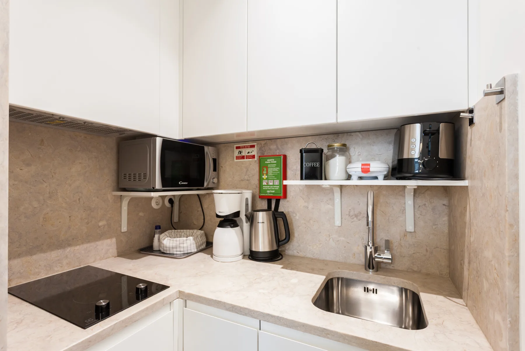 Una encimera de cocina compacta con pequeños electrodomésticos y un fregadero de acero inoxidable.