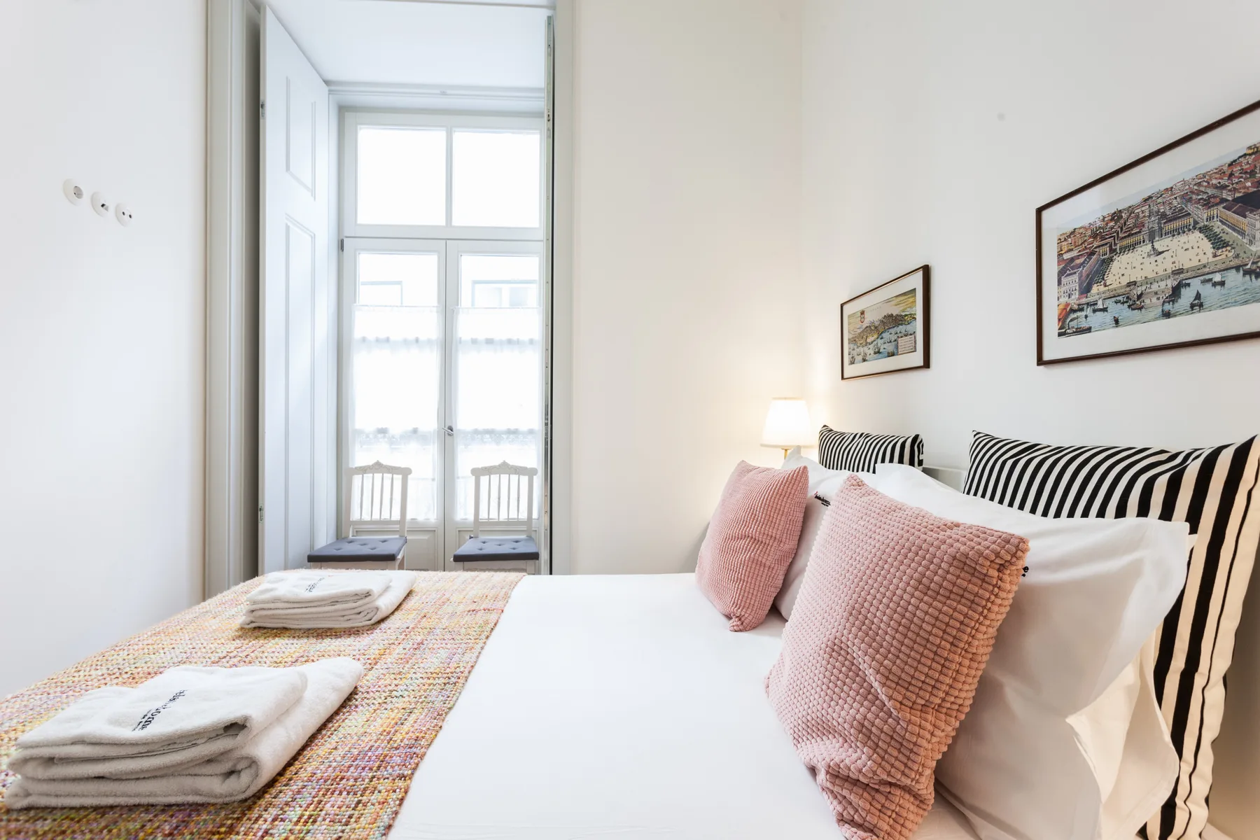 Dormitorio con una cama bien arreglada y cuadros enmarcados en la pared.