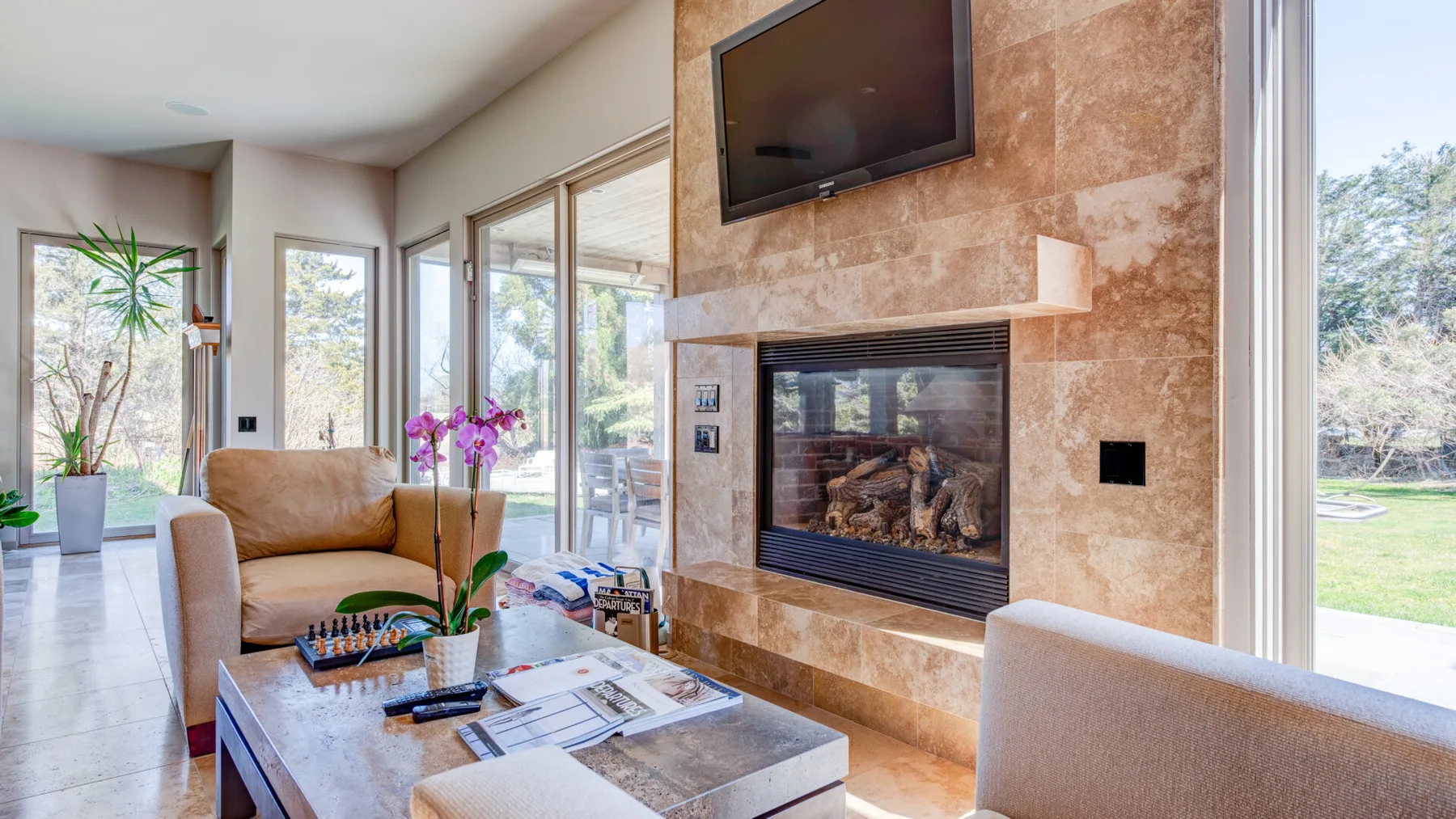Una sala de estar luminosa con chimenea y ventanas grandes.