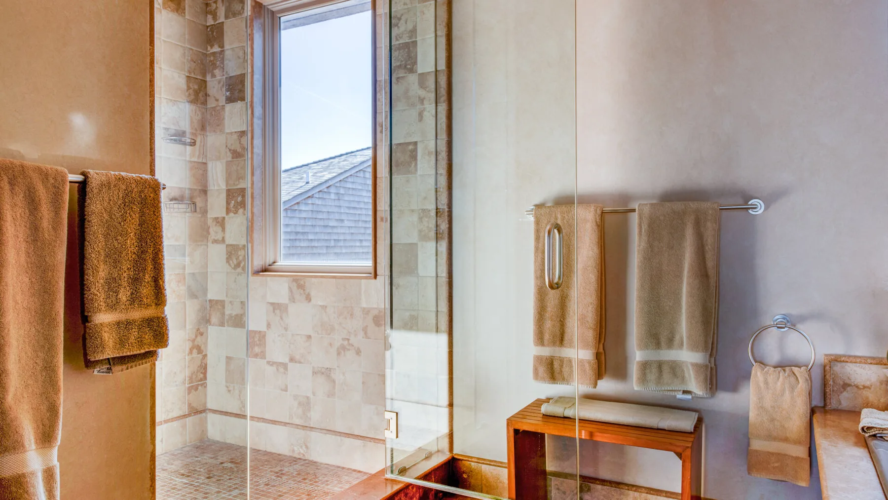 Un baño alicatado con una ducha de vidrio y toallas colgadas en las paredes.