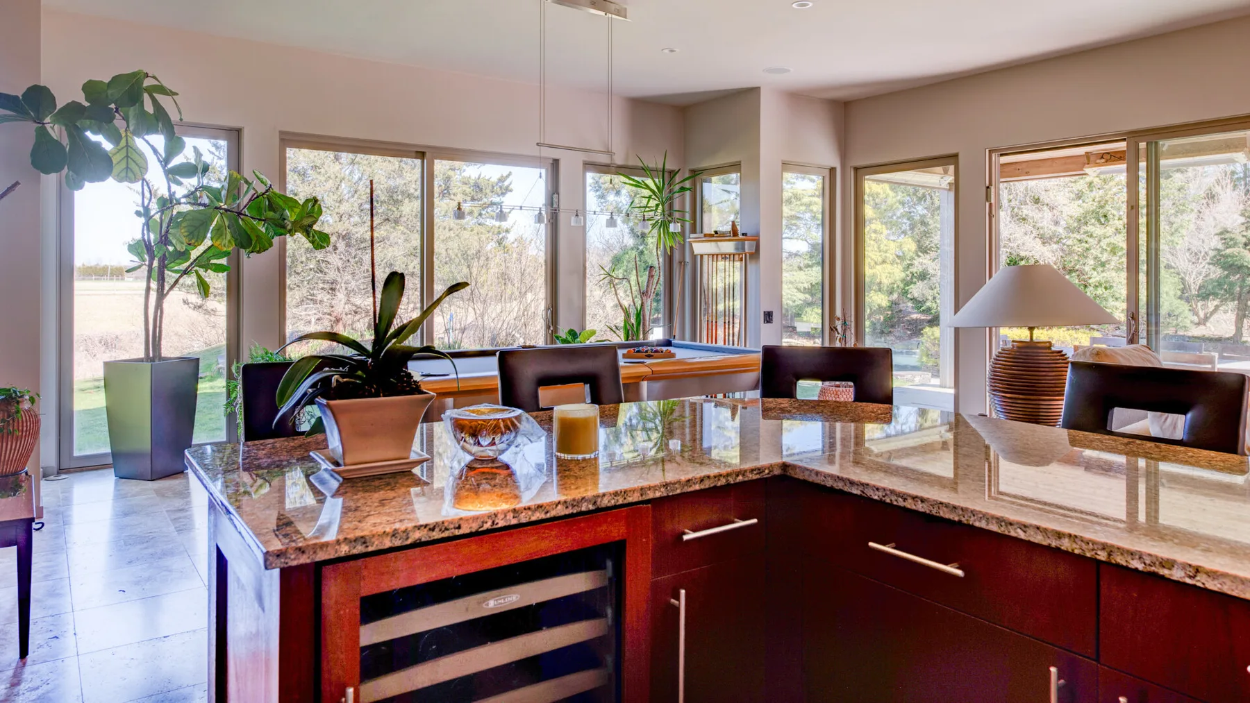 Una cocina luminosa con una isla pulida y ventanas grandes.