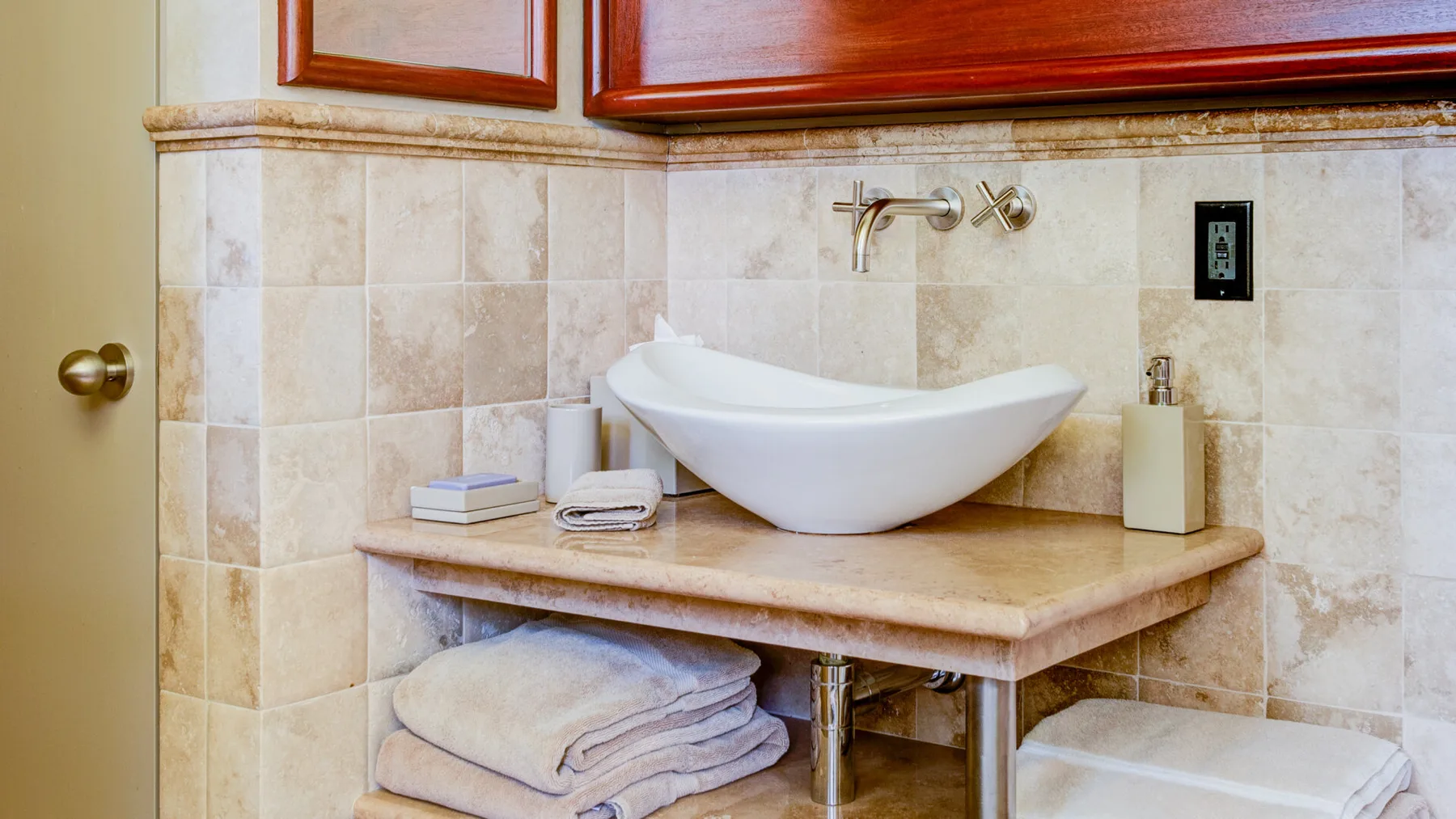 Un mueble de baño con lavabo de sobreponer y toallas dobladas.
