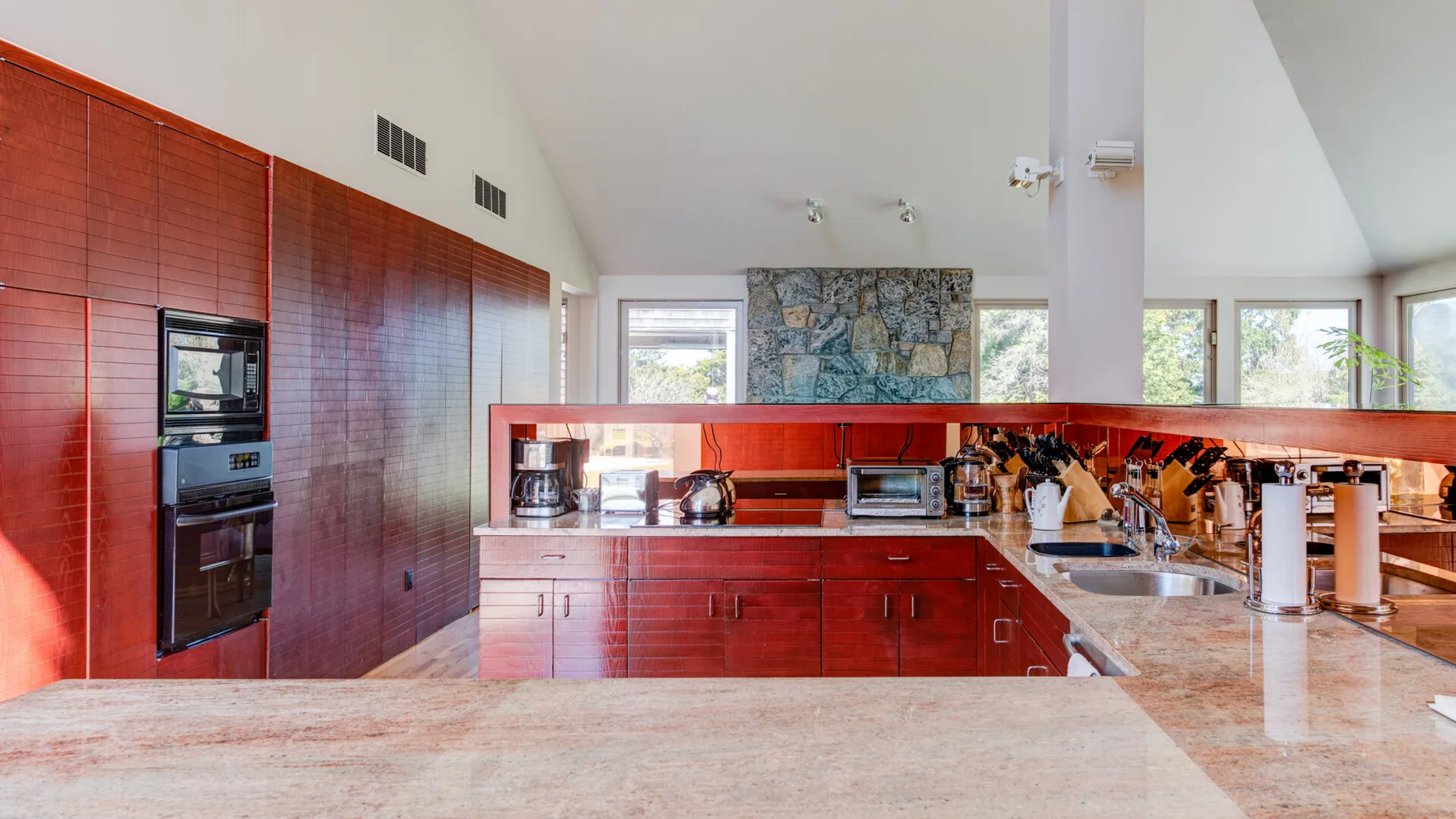 Una cocina amplia con gabinetes rojos, electrodomésticos empotrados y una isla grande.