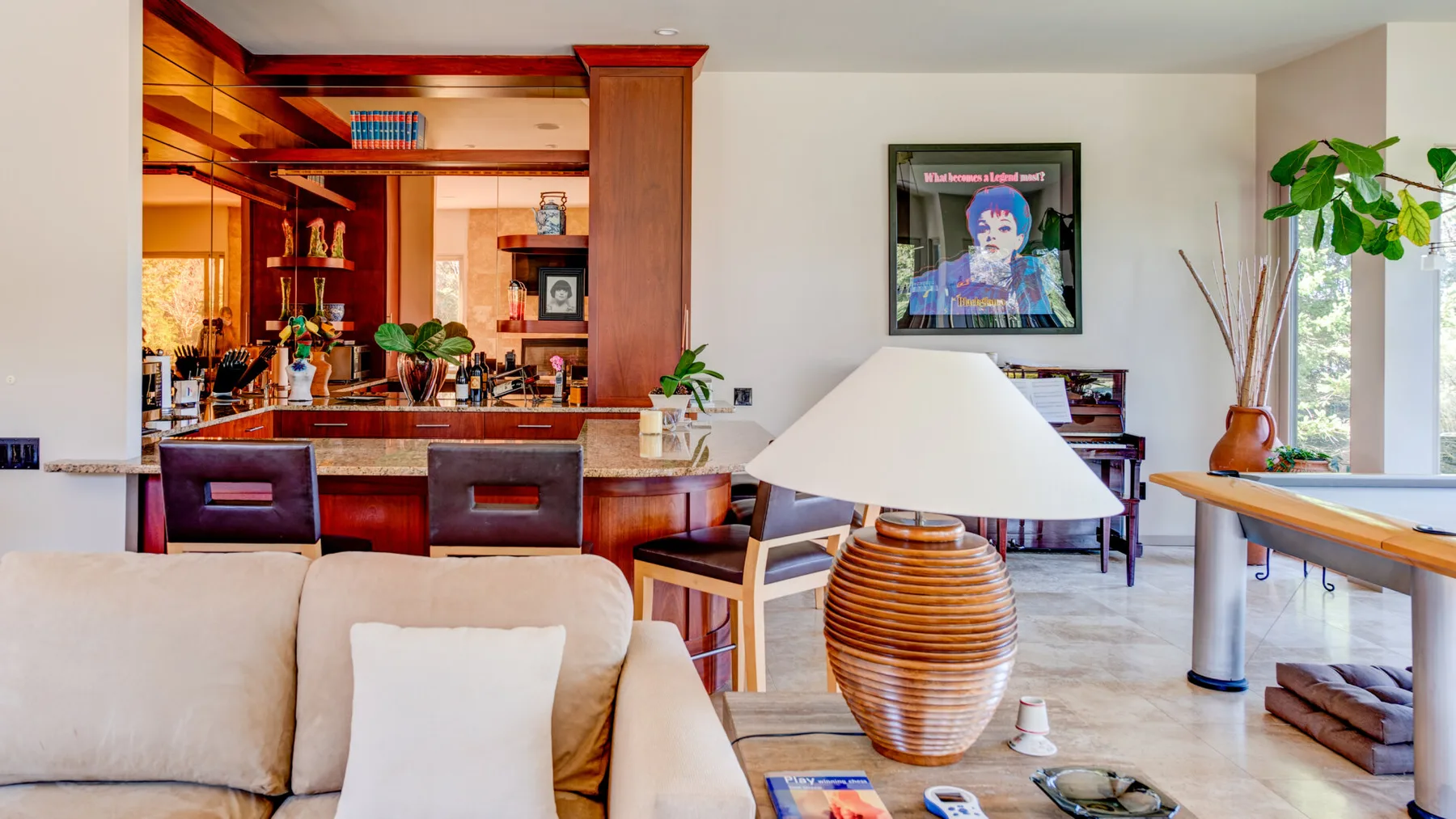 Una sala luminosa con asientos, una lámpara de mesa y una cocina abierta.