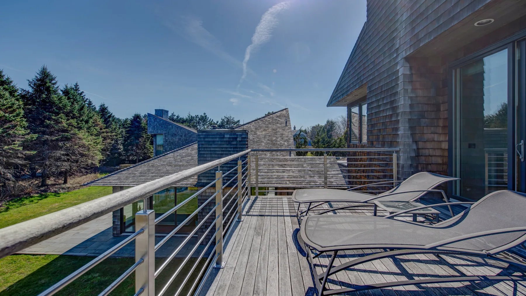 Una terraza de madera con asientos reclinables da a un paisaje arbolado.