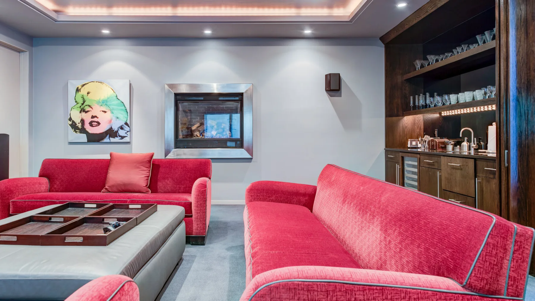 Una sala de estar moderna con asientos rosa intenso y una barra empotrada.