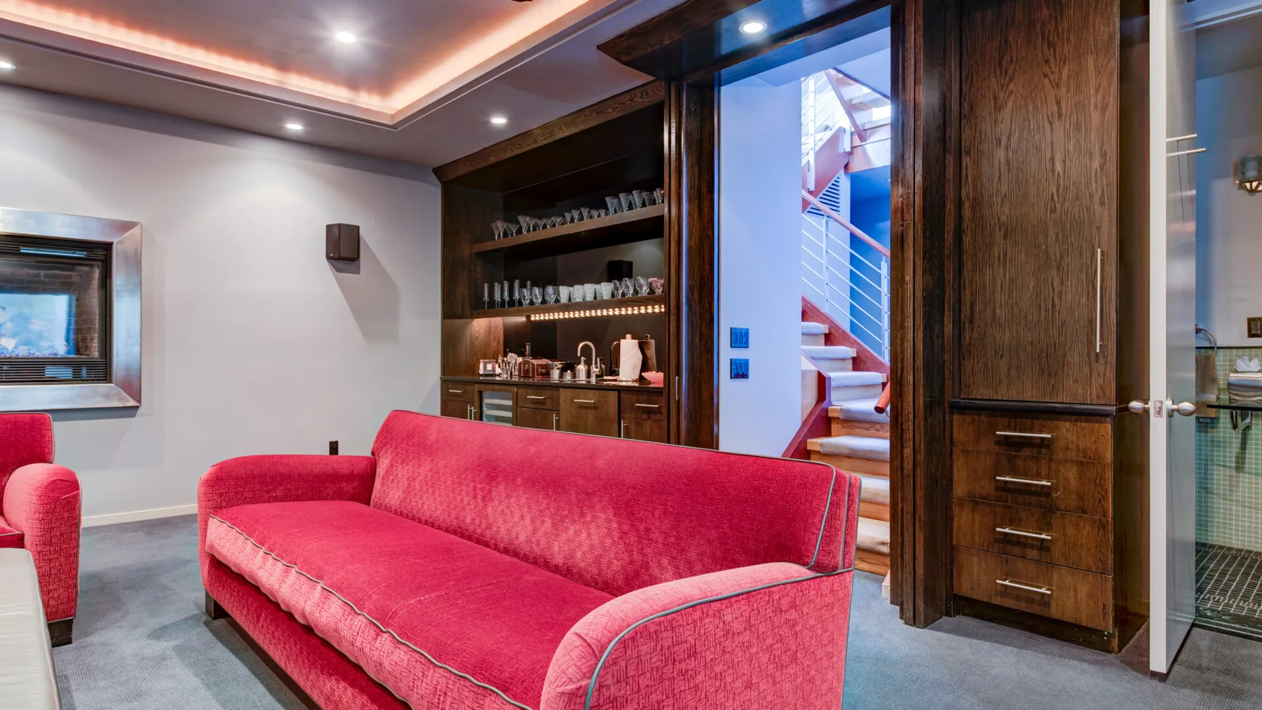 Una sala de estar con asientos rojos y muebles de madera oscura.