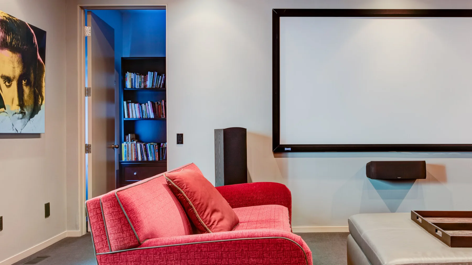Una sala de estar con asientos rojos y una gran pantalla montada en la pared.