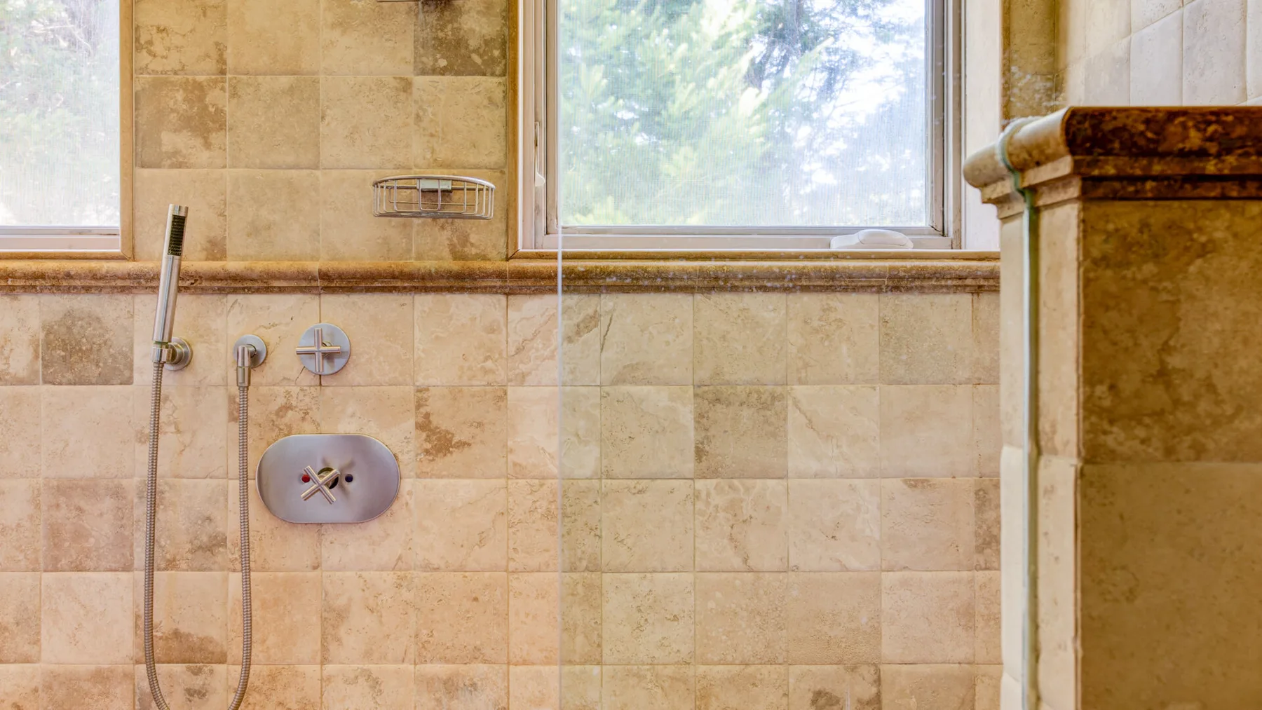 Una ducha de baño con azulejos está debajo de una ventana amplia.