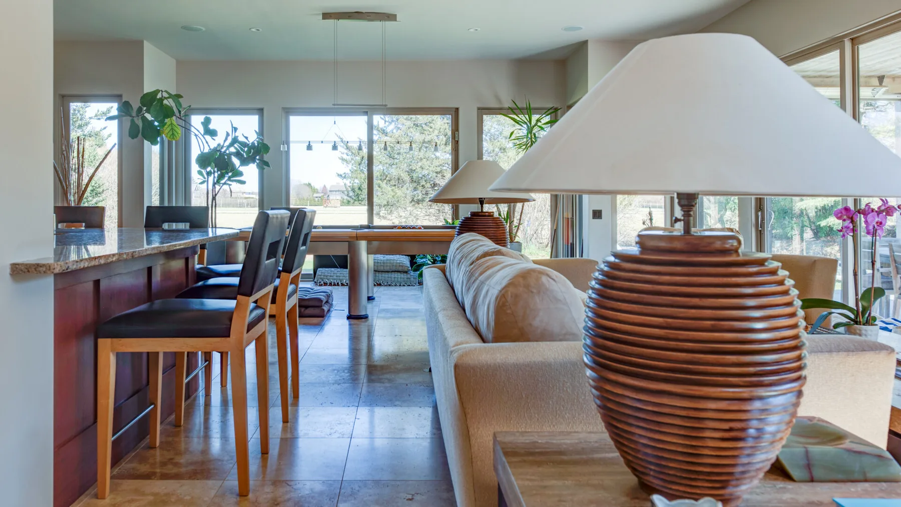 Una sala-comedor de planta abierta con ventanales y una lámpara de mesa.