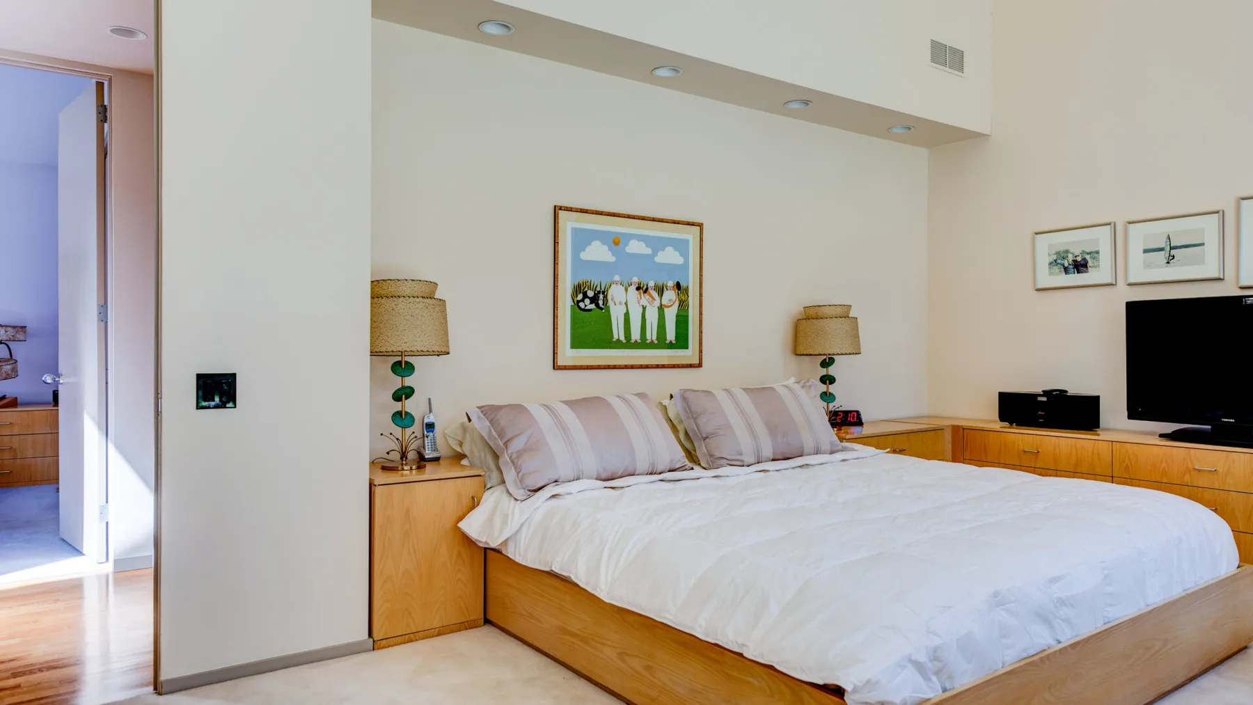 Un dormitorio con una cama grande, mesitas de madera y cuadros enmarcados.